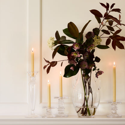 Lumière Glass Single Candlestick, clear glass with sleek edges, holding a lit cream taper candle.