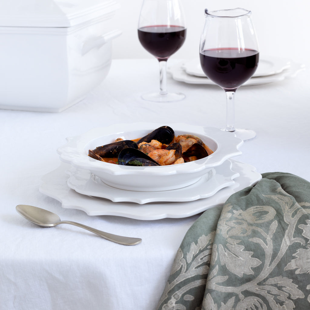 White ceramic Lungarno salad/dessert plate with sculptural rim, holding a seafood dish.
