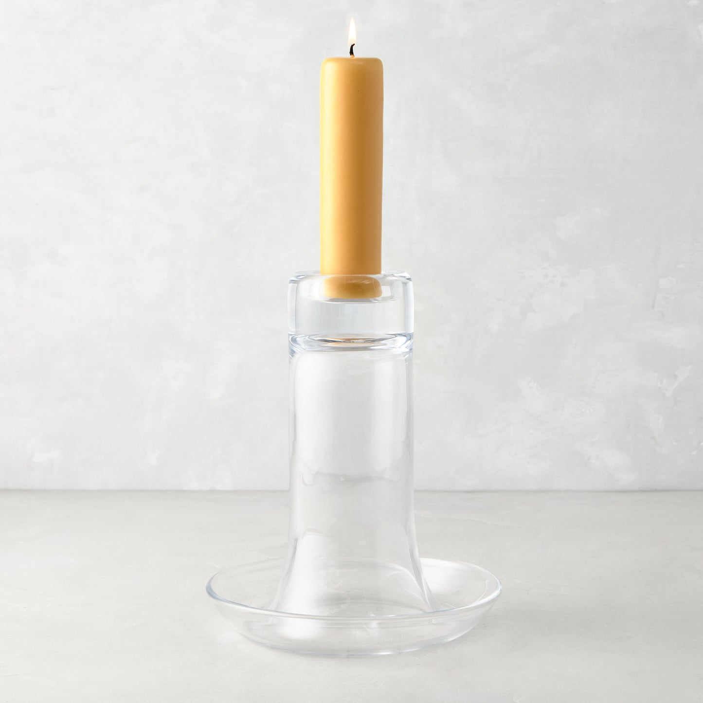 Large Luz clear glass candleholder with a lit amber pillar candle.