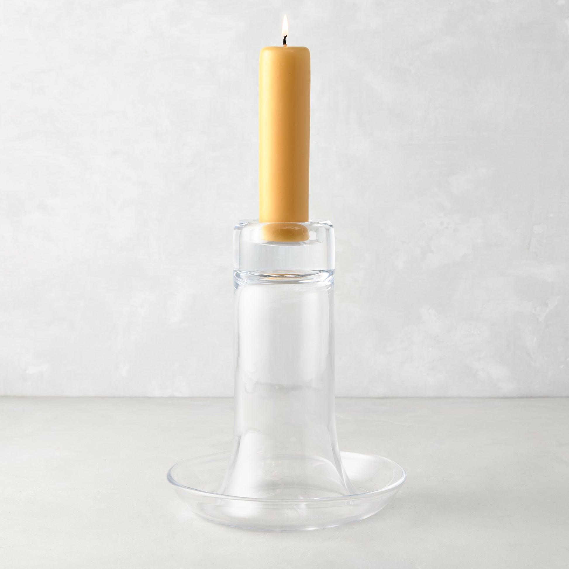 Large Luz clear glass candleholder with a lit amber pillar candle.