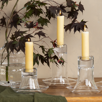 Three clear glass Luz Candleholders, medium and varying heights, with amber pillar candles.