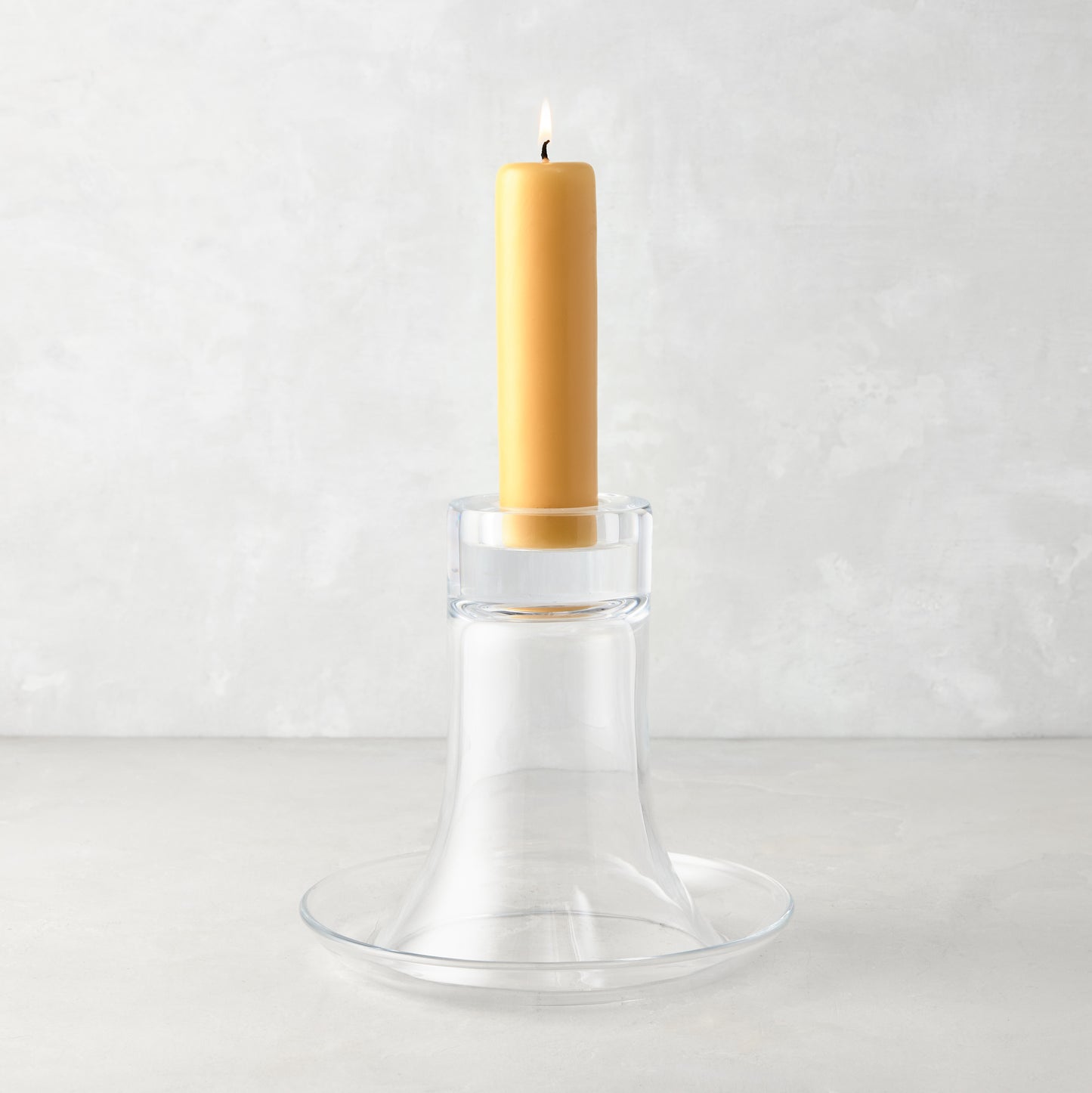Medium Luz clear glass candleholder with a lit amber pillar candle.