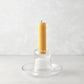 Small clear glass Luz Candleholder with a lit amber pillar candle.