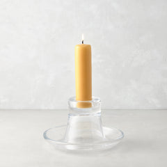 Small clear glass Luz Candleholder with a lit amber pillar candle.