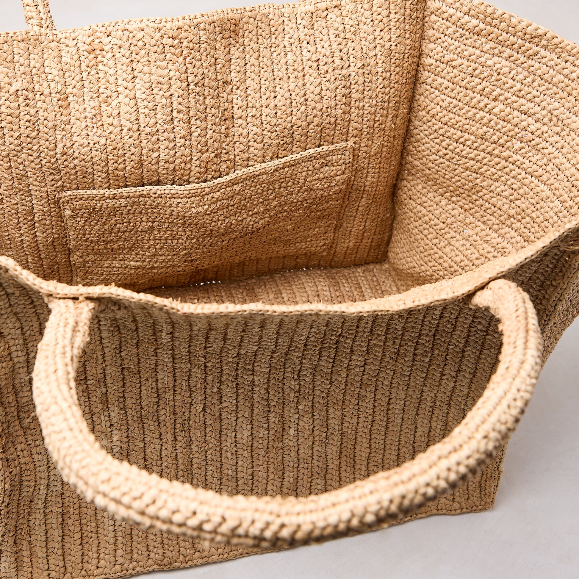 Handcrafted Madagascar Packable Raffia Tote Bag, natural tea-dyed, crocheted texture, with an interior pocket.