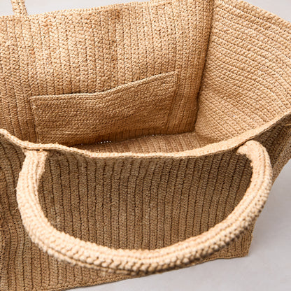 Handcrafted Madagascar Packable Raffia Tote Bag, natural tea-dyed, crocheted texture, with an interior pocket.