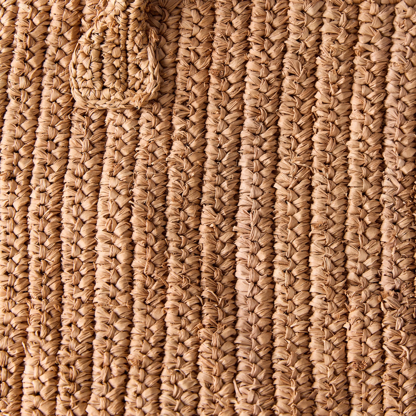 Close-up of a Madagascar Packable Raffia Tote Bag, showing its natural tea-dyed, crocheted raffia texture.