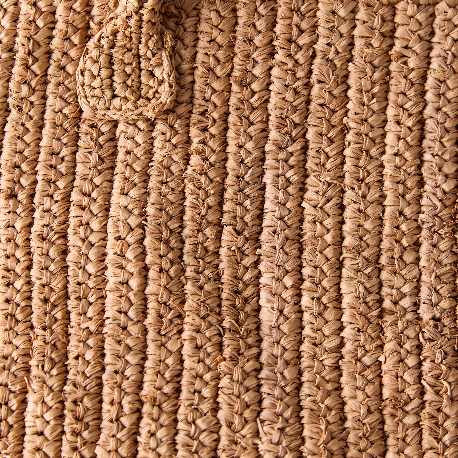 Close-up of a Madagascar Packable Raffia Tote Bag, showing its natural tea-dyed, crocheted raffia texture.