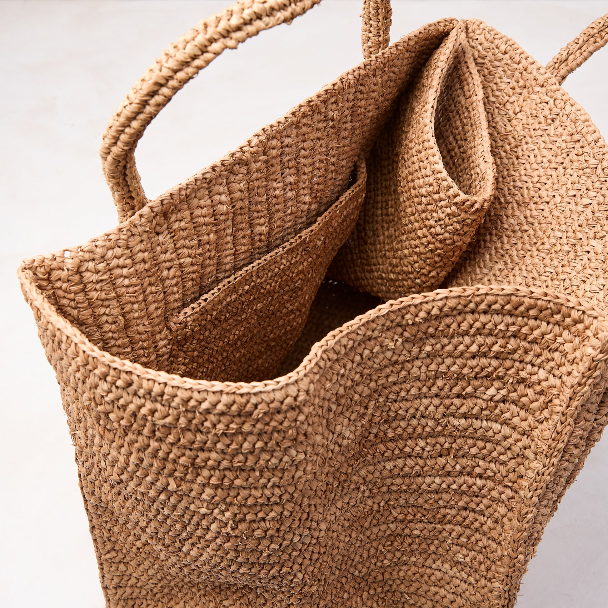Handcrafted, packable Madagascar Raffia tote bag with crocheted texture and natural tea-dyed brown color.