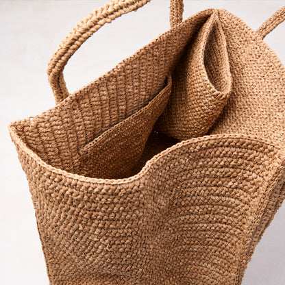 Handcrafted, packable Madagascar Raffia tote bag with crocheted texture and natural tea-dyed brown color.