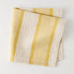 Madras Marigold and Natural Stripe Cotton Napkin, folded, with yellow stripes on a beige base.