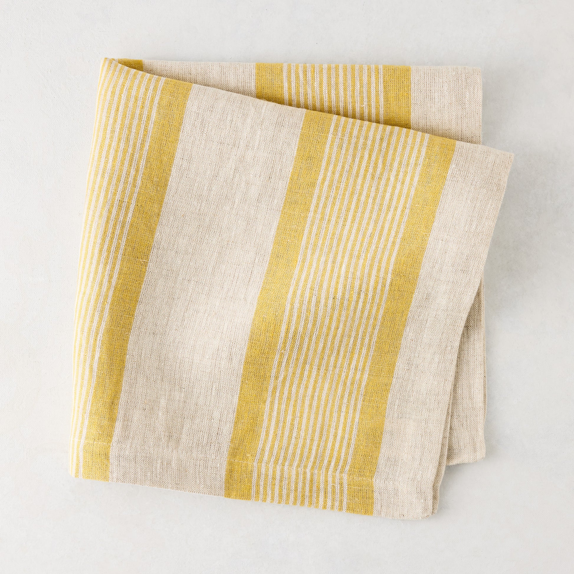 Madras Marigold and Natural Stripe Cotton Napkin, folded, with yellow stripes on a beige base.