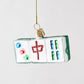 Hand-painted glass Mahjong tile Christmas ornament with glittered red and green details hanging on a gold string.