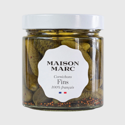 Maison Marc Cornichons Fins in a clear glass jar with a white lid and label, showing green pickles and spices.