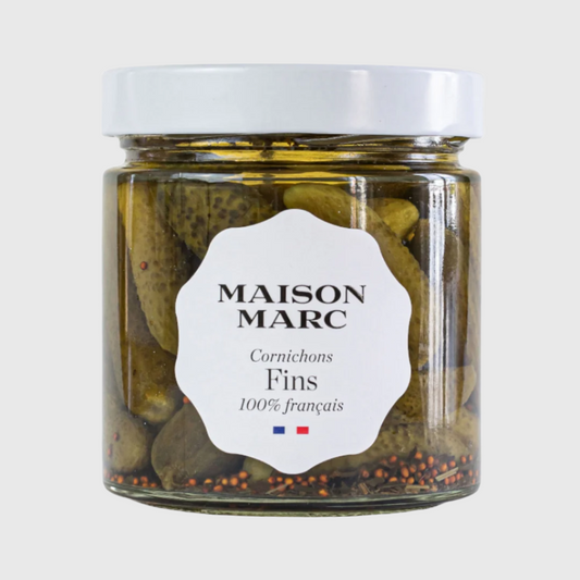 Maison Marc Cornichons Fins in a clear glass jar with a white lid and label, showing green pickles and spices.