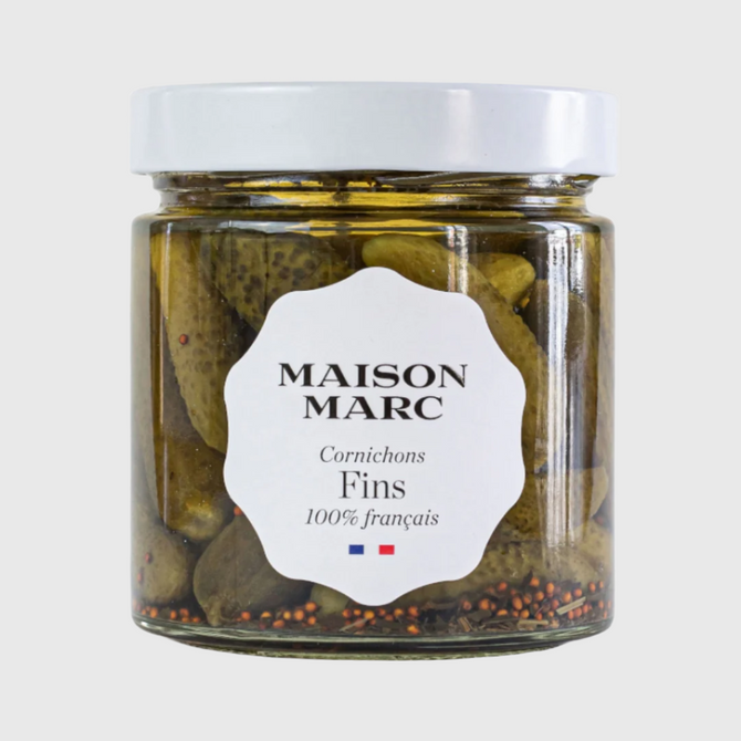 Maison Marc Cornichons Fins in a clear glass jar with a white lid and label, showing green pickles and spices.