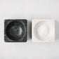 Black and white square marble pinch bowls, one filled with white salt, on a light background.