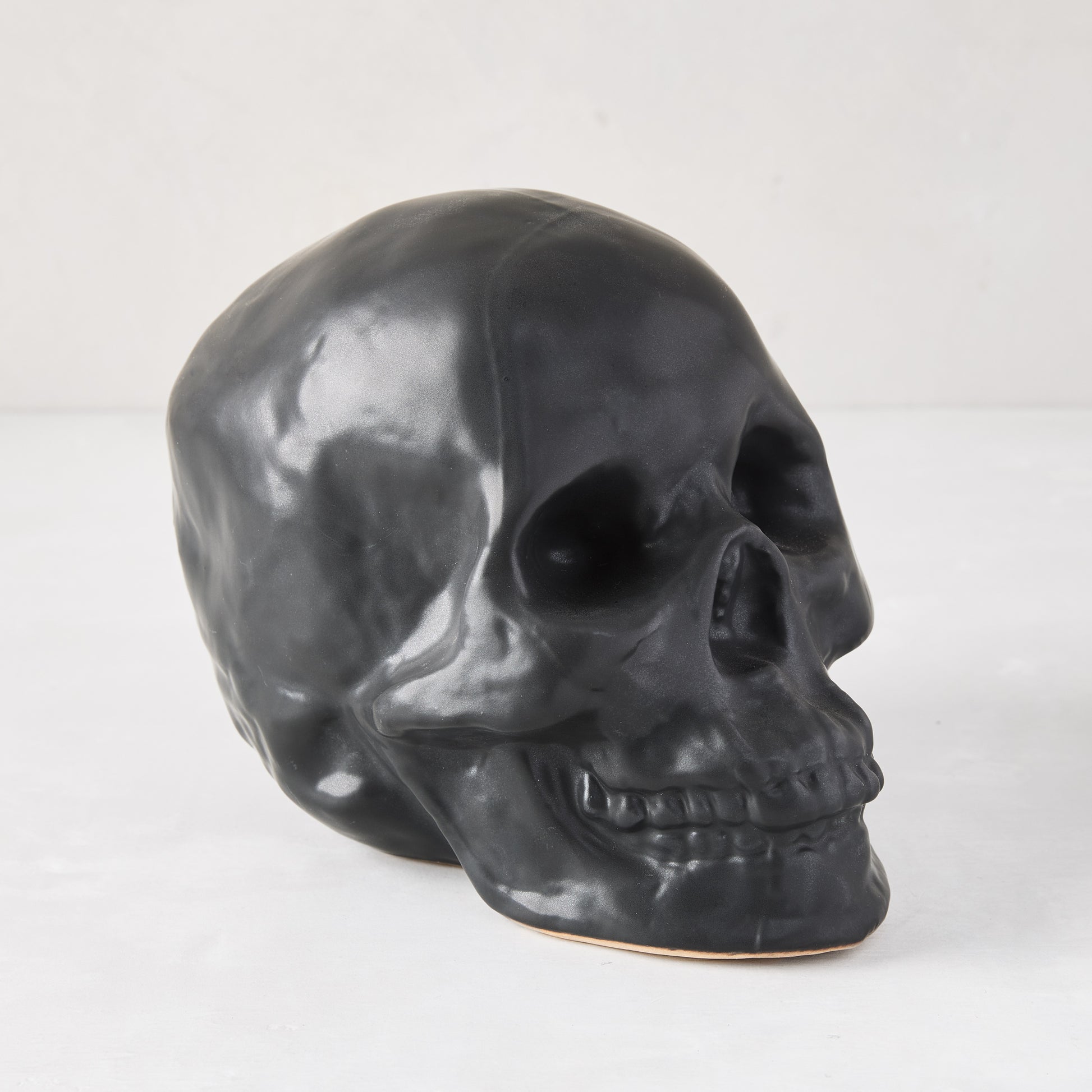 Matte black ceramic Halloween skull, 5.5"H x 7"W, with realistic details.