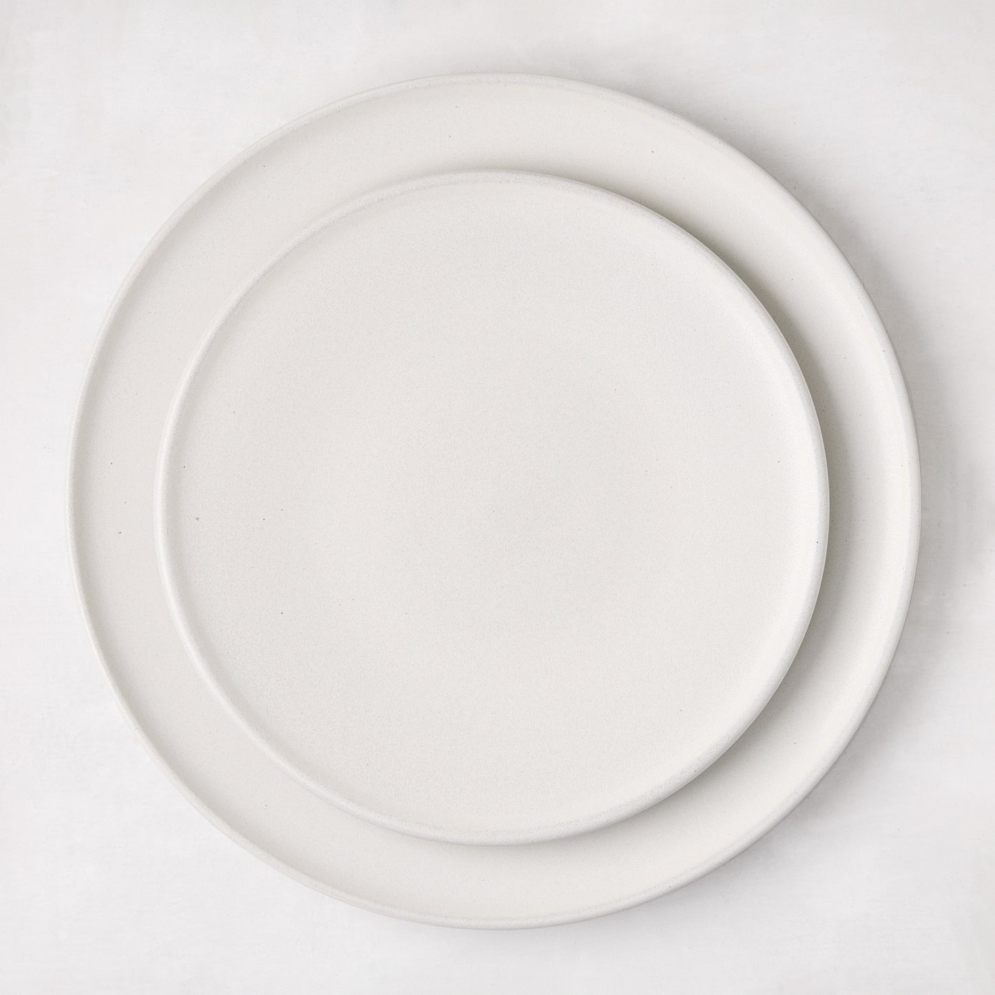 Matte white stoneware dinner plate with a smaller matching plate stacked on top.