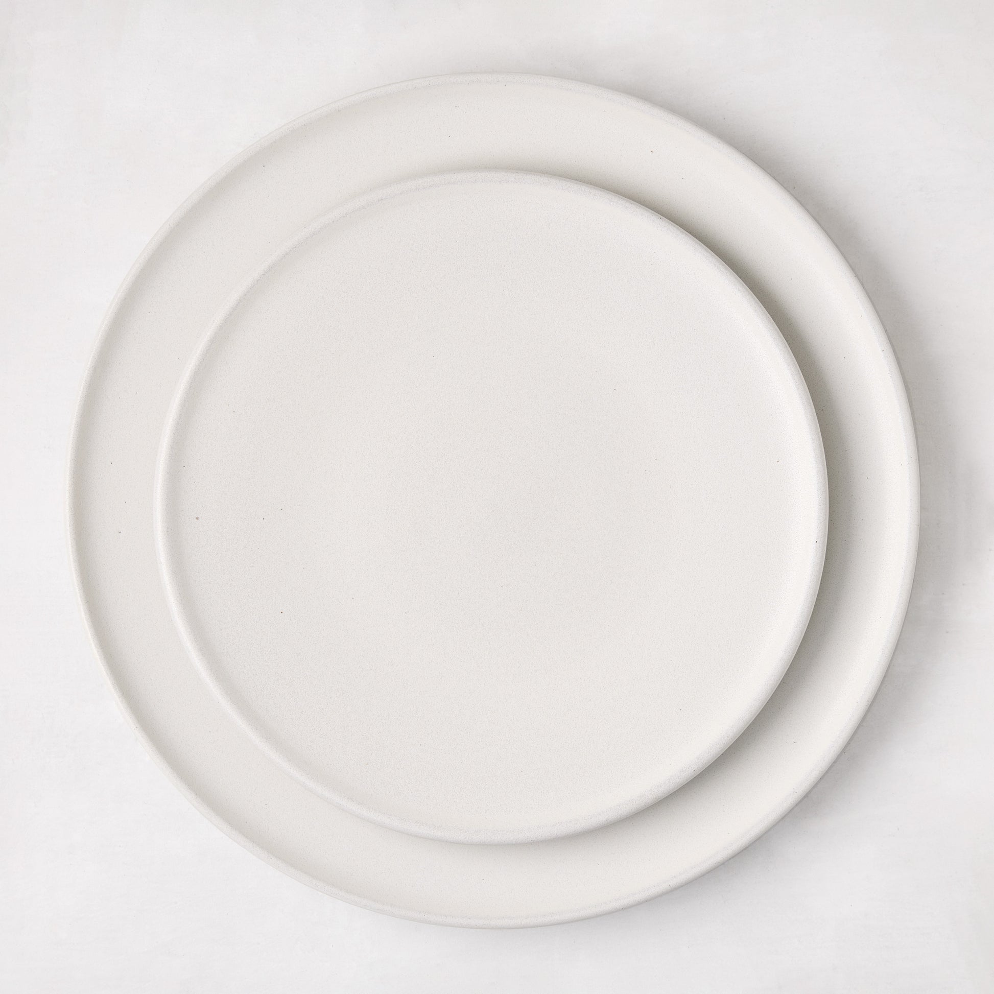 Matte white stoneware dinner plate with a smaller matching plate stacked on top.