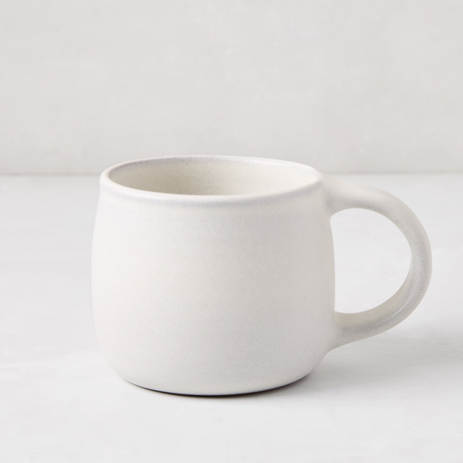 Matte white stoneware mug with a smooth glaze and subtle grey speckles, from the Matte White Stoneware Collection.
