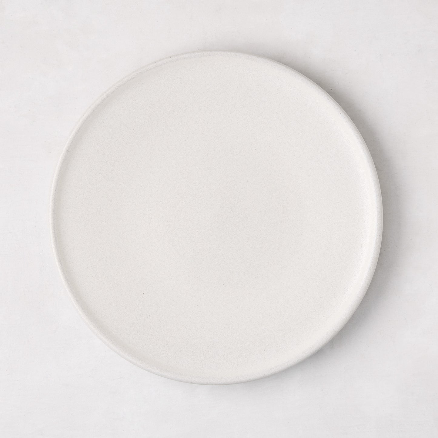 Matte white stoneware salad plate with a smooth glaze and subtle grey speckles.