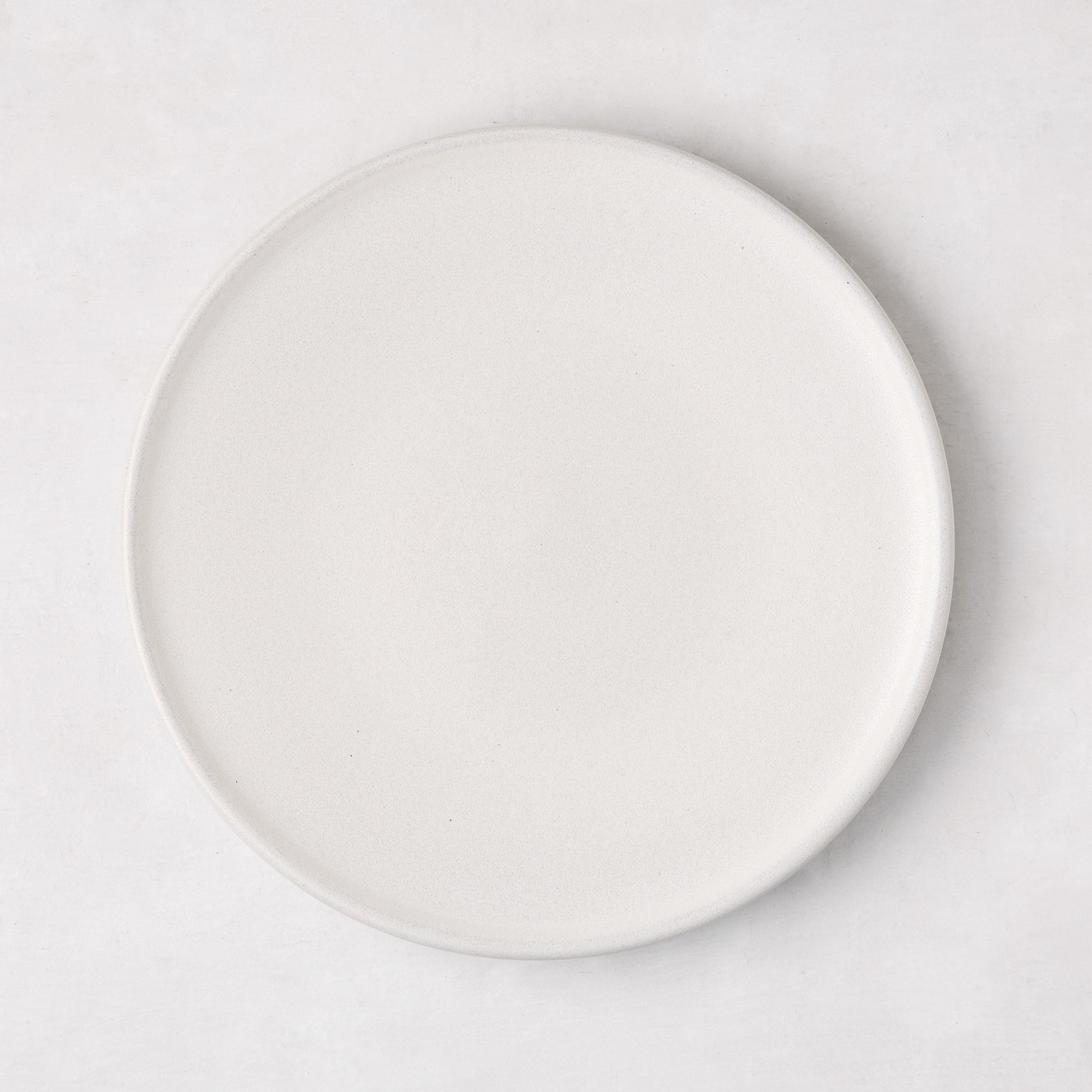 Matte white stoneware salad plate with a smooth glaze and subtle grey speckles.