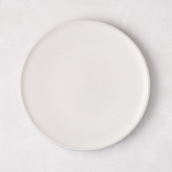 Matte white stoneware salad plate with a smooth glaze and subtle grey speckles.