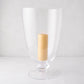 Large Mayfair clear glass hurricane with decorative base, holding a lit cream pillar candle.