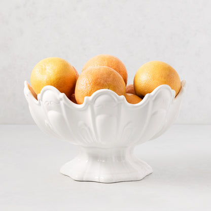 White ceramic scallop serve bowl filled with grapefruits.