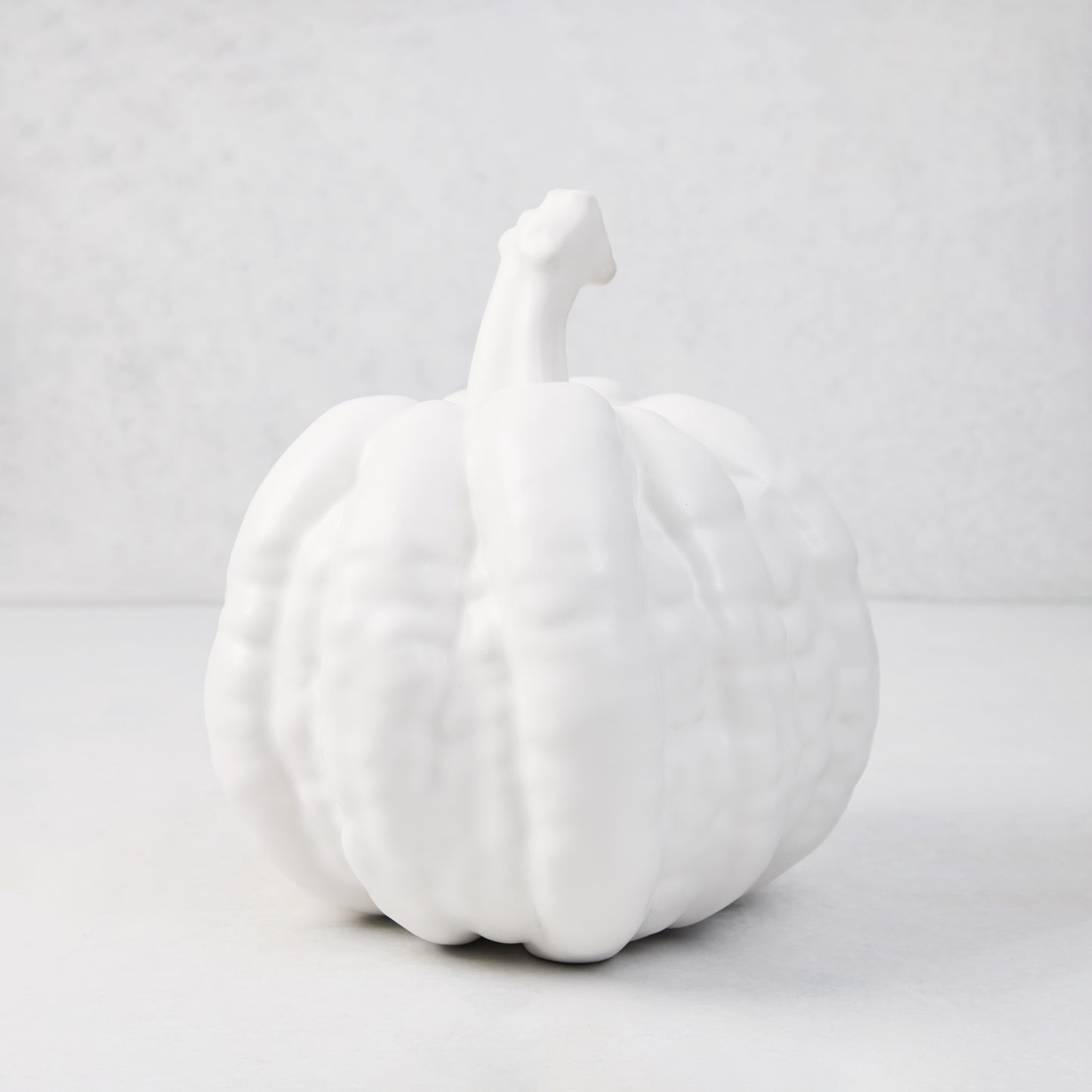 Small matte white ceramic pumpkin, 8.5"H x 9"W, with ribbed texture and short stem.