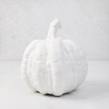 Small matte white ceramic pumpkin, 8.5"H x 9"W, with ribbed texture and short stem.