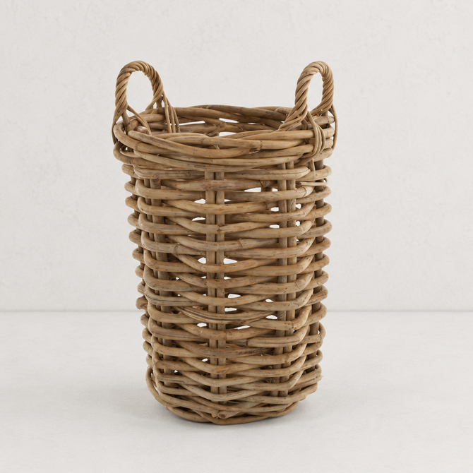 Medium round basket made of natural sandblasted rattan with two side handles on a white background.