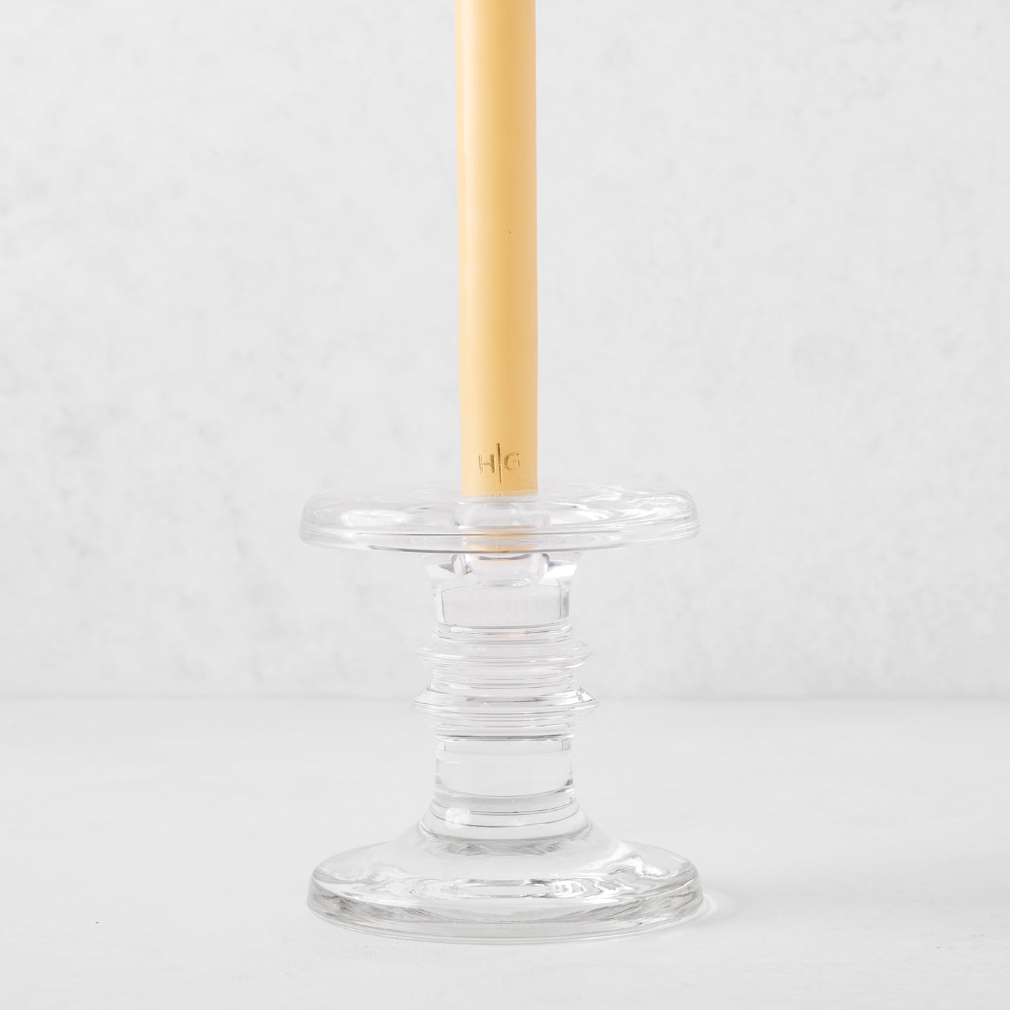 Medium clear glass taper candleholder with ridges, holding a beige taper candle.