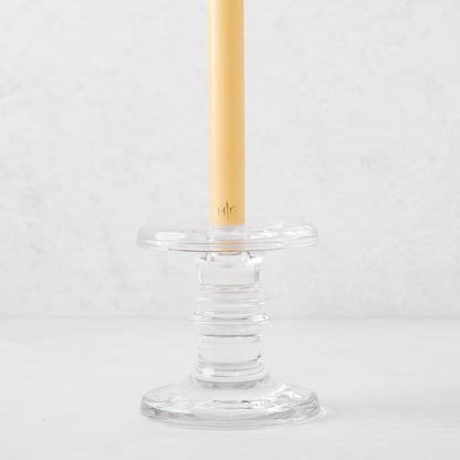 Medium clear glass taper candleholder with ridges, holding a beige taper candle.