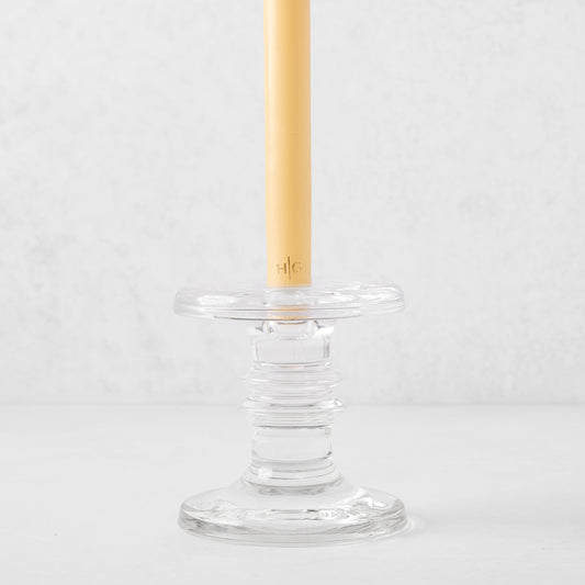 Medium clear glass taper candleholder with ridges, holding a beige taper candle.