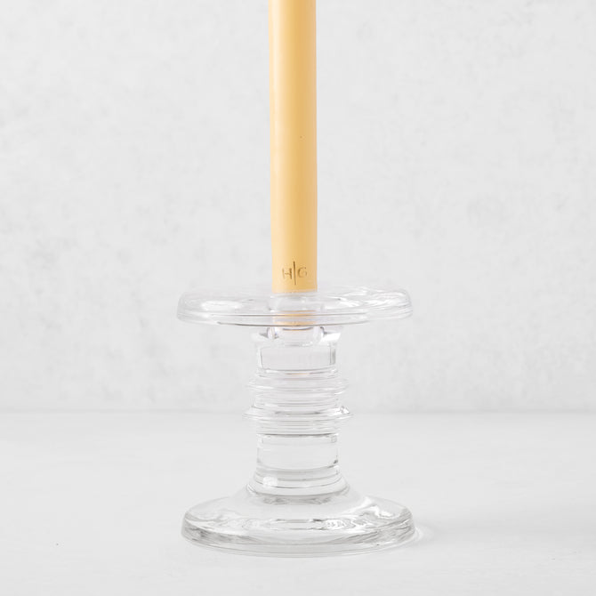 Medium clear glass taper candleholder with ridges, holding a beige taper candle.