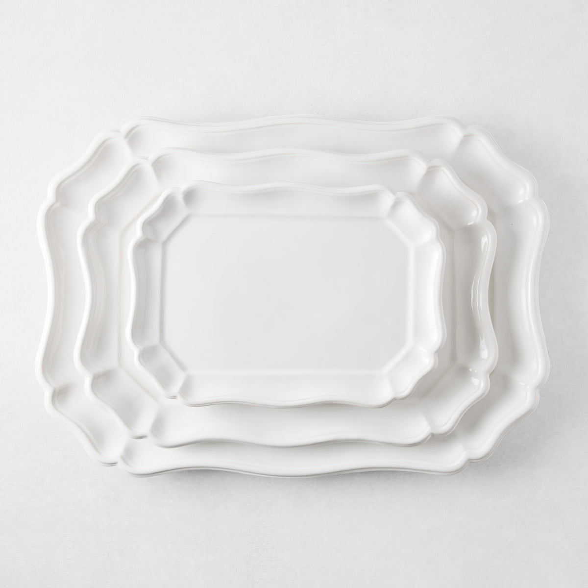Three nested white ceramic Torcello serve platters with scalloped edges and a glossy finish on a white background.