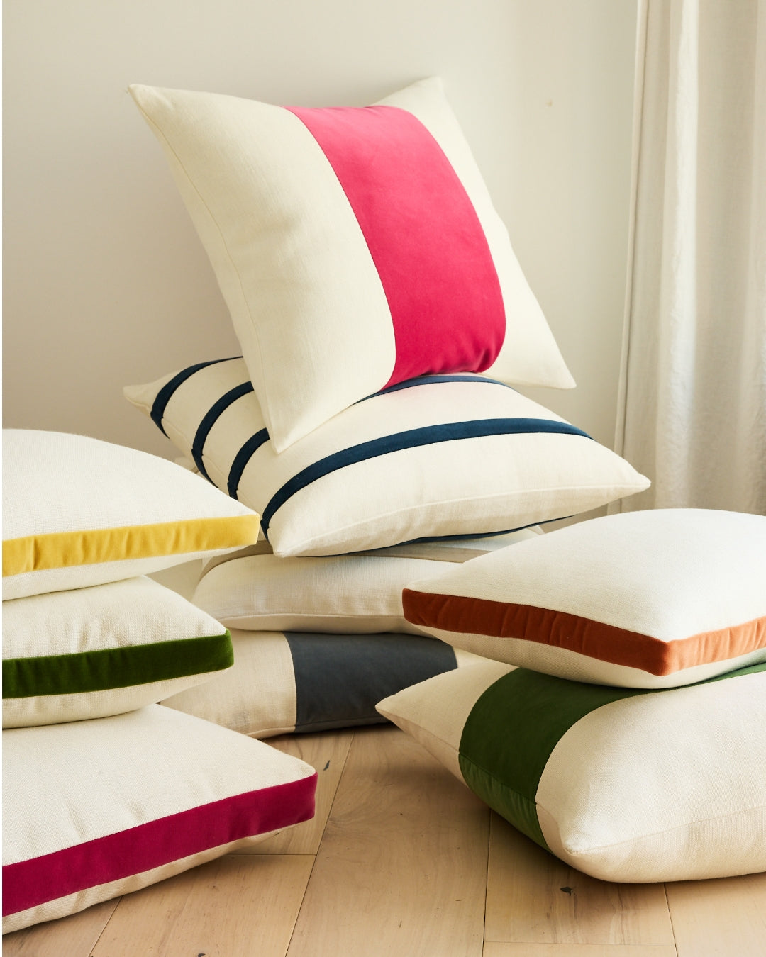 Stack of Hudson Grace lumbar pillows: cream linen with velvet stripes in yellow, green, navy, rust, and hot pink.