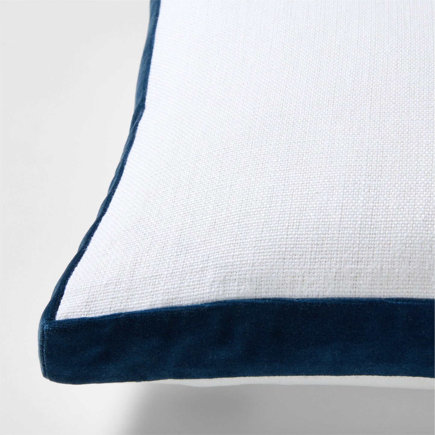 White linen lumbar pillow with midnight blue velvet gusset trim.