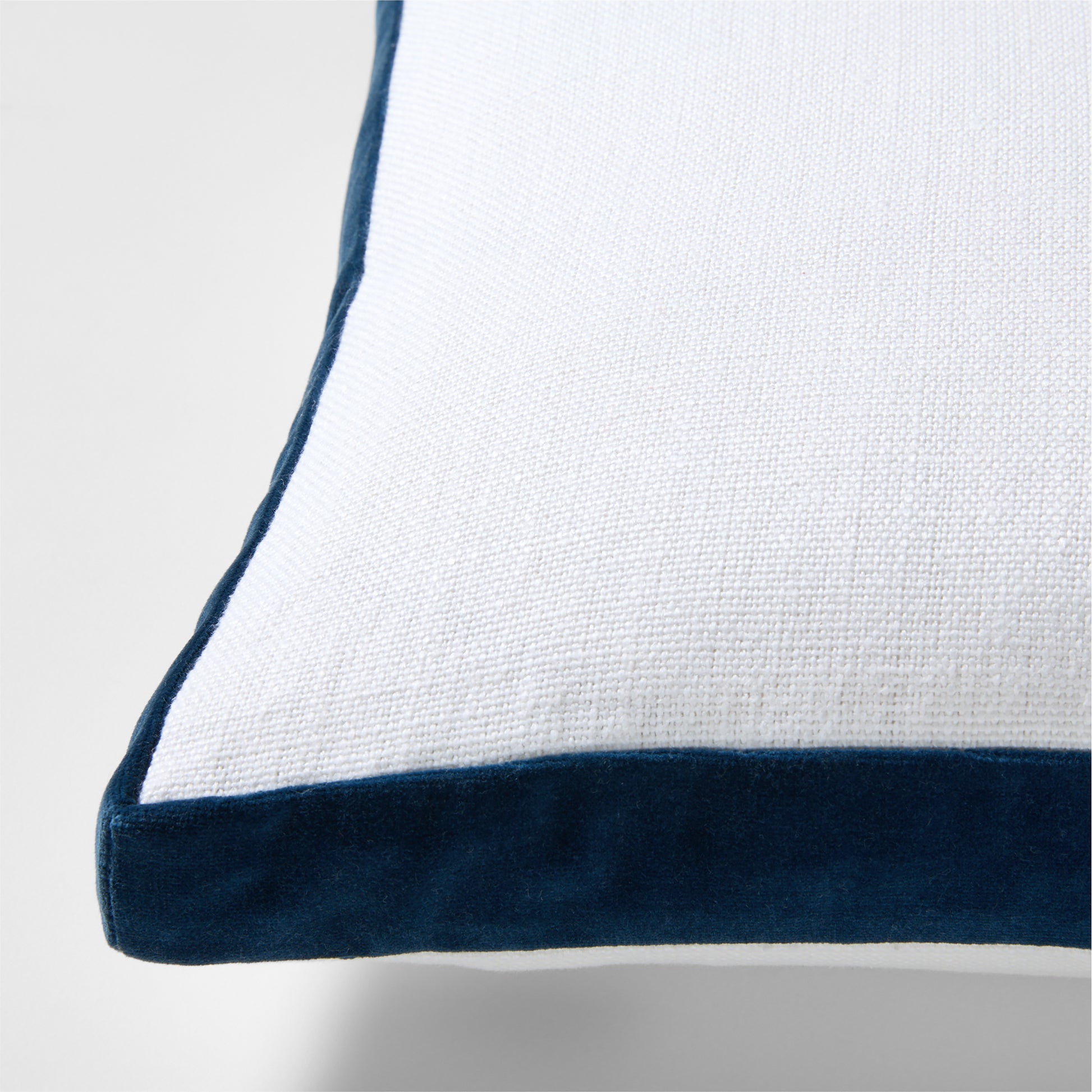 White linen lumbar pillow with midnight blue velvet gusset trim.