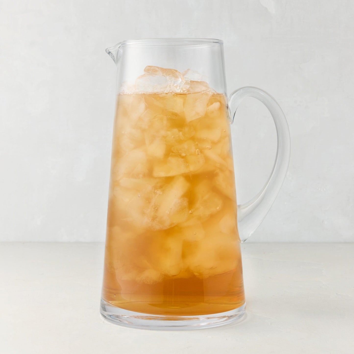 Midtown Tapered Glass Pitcher filled with iced tea, featuring a clear glass handle and sleek design.