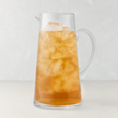 Midtown Tapered Glass Pitcher filled with iced tea, featuring a clear glass handle and sleek design.