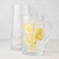Two clear Midtown Tapered Glass Pitchers, one empty and one filled with lemonade and ice.