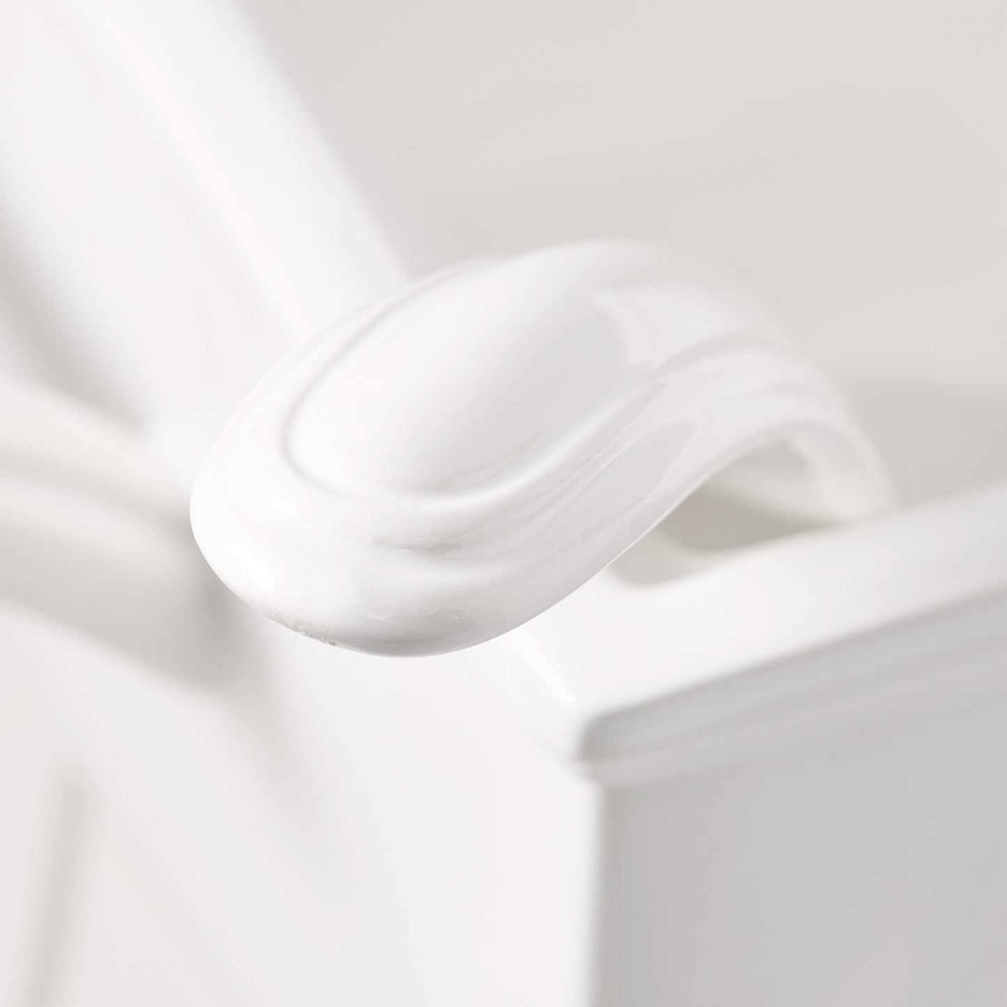 Close-up of a white ceramic Milano soup tureen handle, showing its elegant curved design.