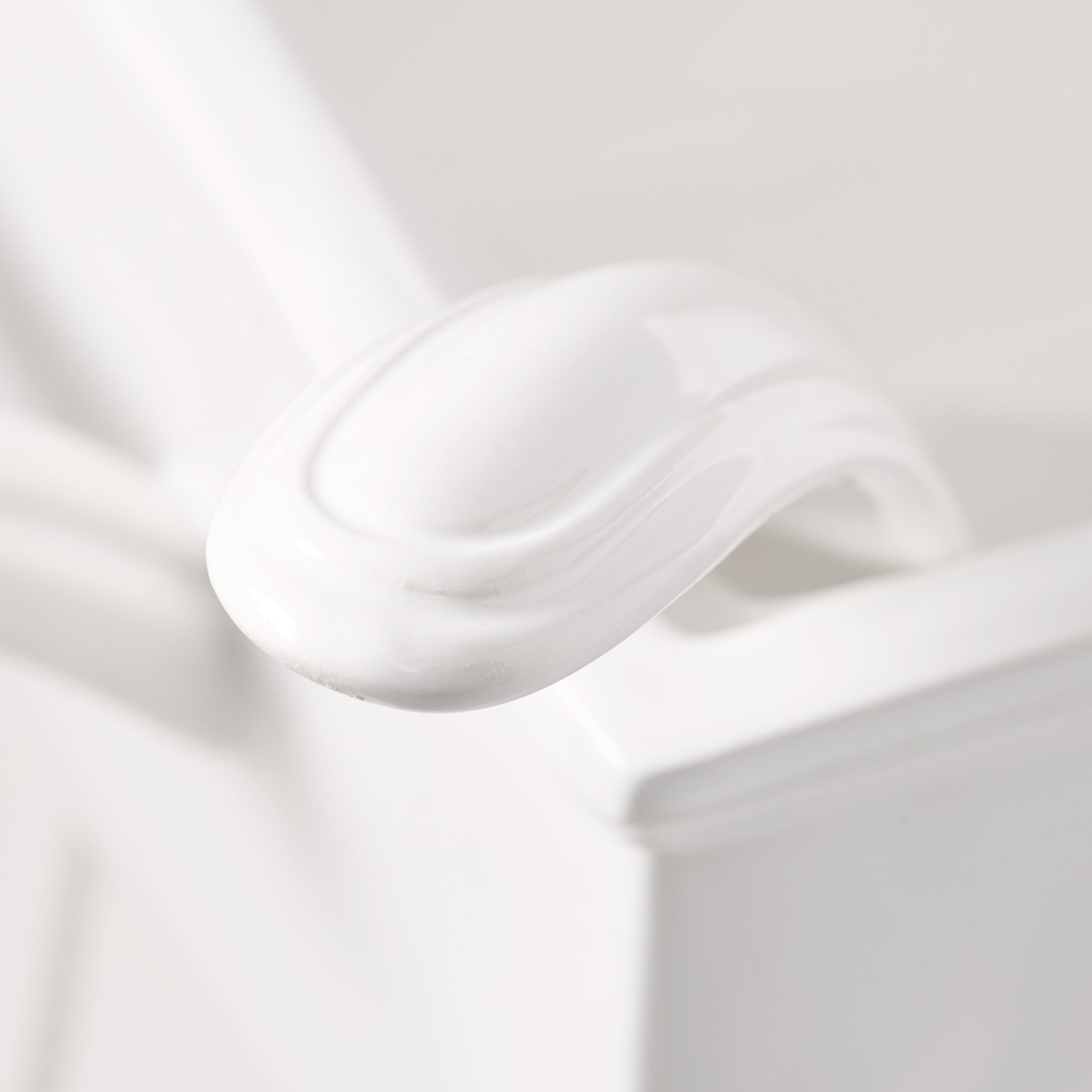Close-up of a white ceramic Milano soup tureen handle, showing its elegant curved design.