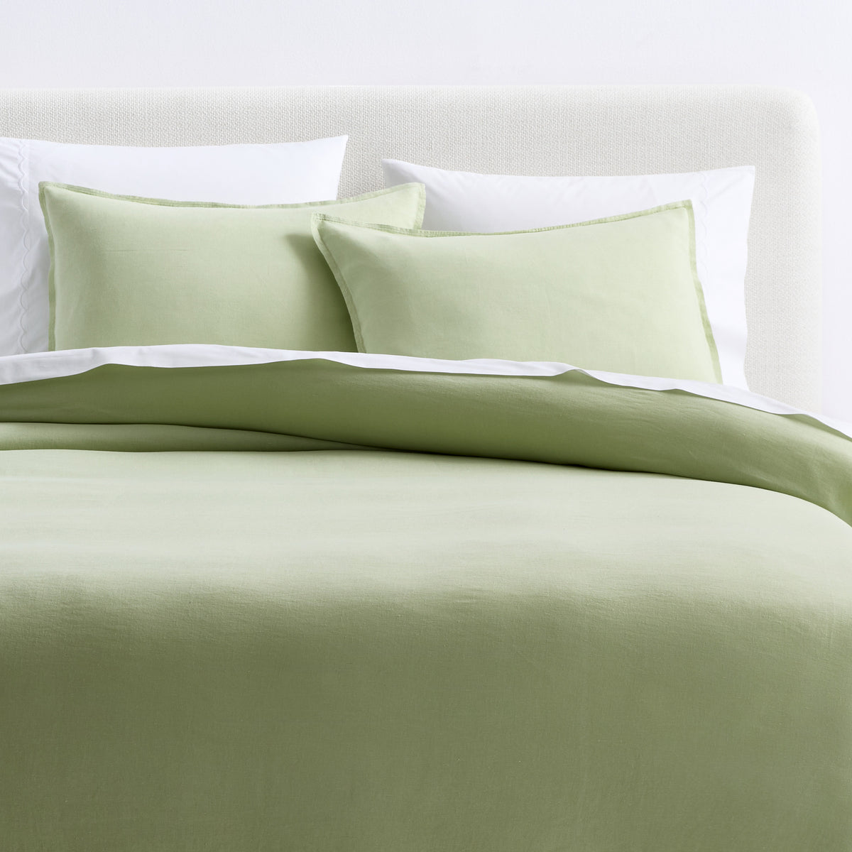 Mint green European washed linen duvet cover and two matching shams on a bed with white pillows.