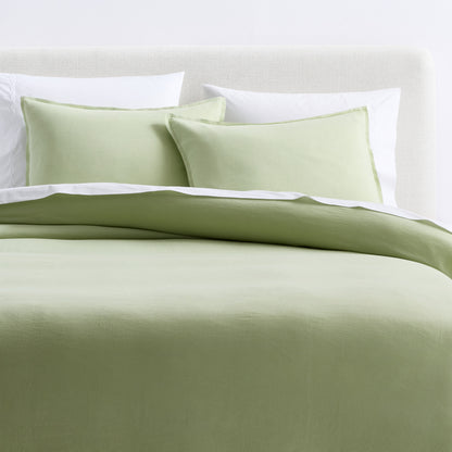 Mint green European washed linen duvet cover and two matching shams on a bed with white pillows.