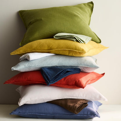 Stack of colorful European washed linen pillow shams in various shades including mint green, yellow, red, and blue.