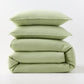 Stacked mint green European washed linen duvet cover and two matching pillow shams on a white background.